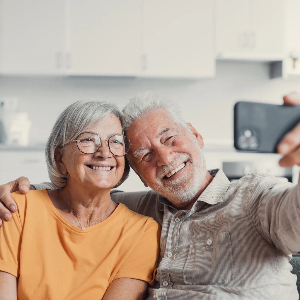 happy elderly couple smiling and taking a selfie with smartphone