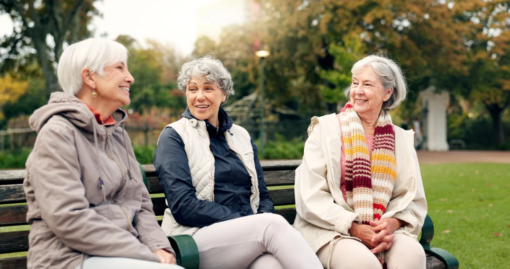 senior women friends pointing and talking in a park, enjoying retirement and nature